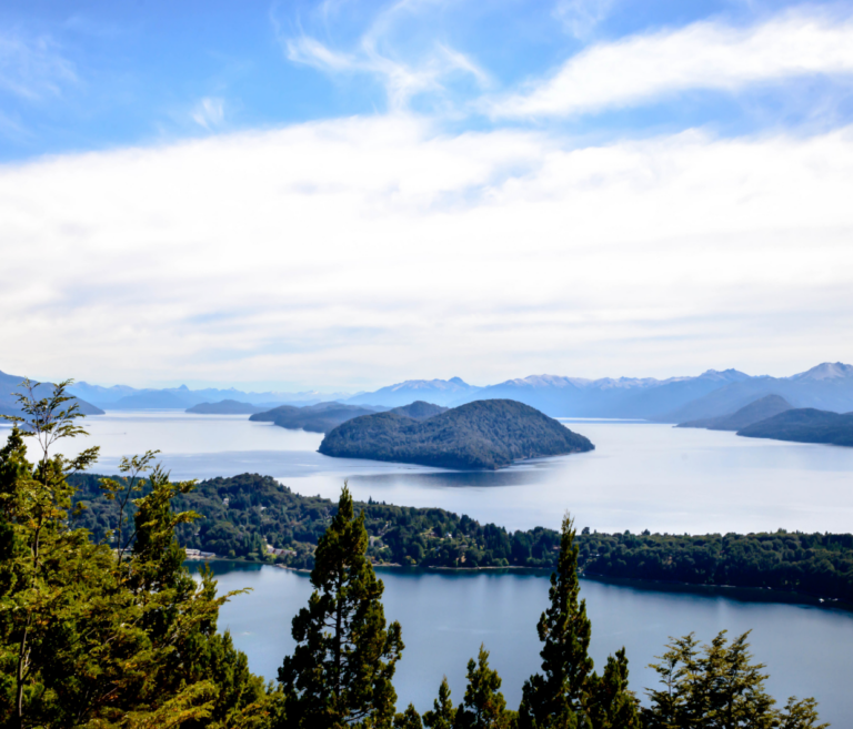 A landscape view from atop a hill, surrounded by virgin forests, and overlooking the water with small islands