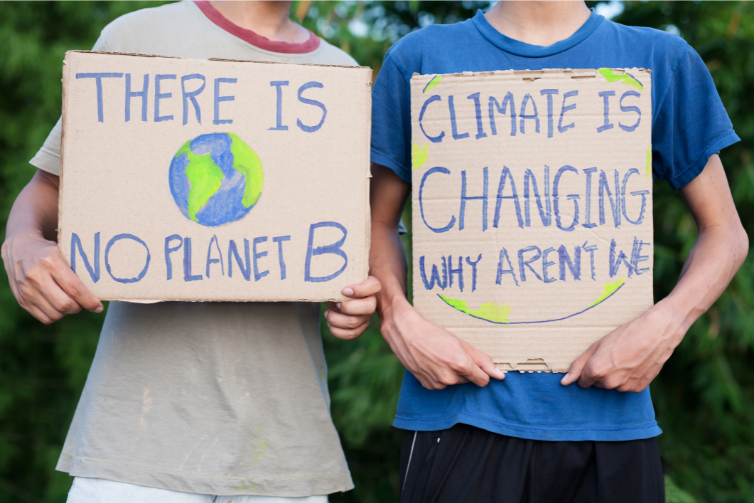 Two young children holding placards about climate change. One says, there is no planet B, and the other sign says the climate is changing why aren't we