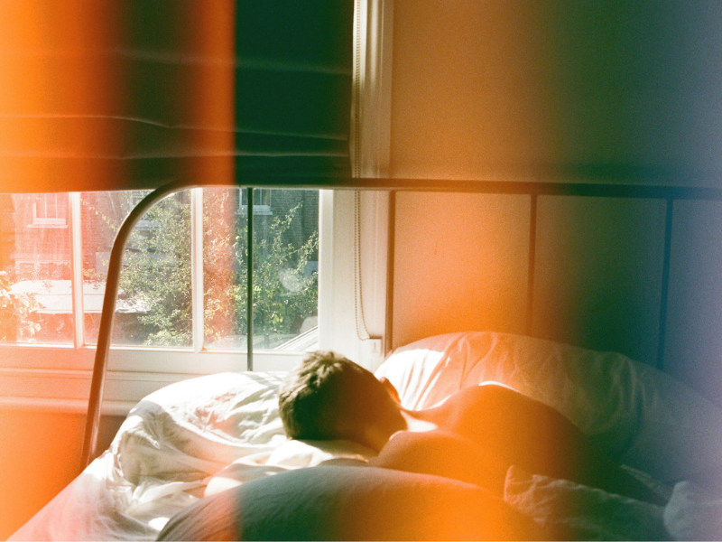 Semi-lit bedroom with back of boy's head sleeping in bed. Boost your attention with healthy sleep habits. 