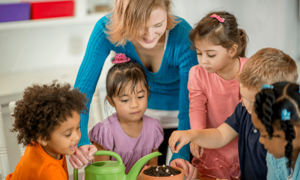 A teacher wearing a blue knit pullover with her captive young and diverse audience learning about planting seeds.