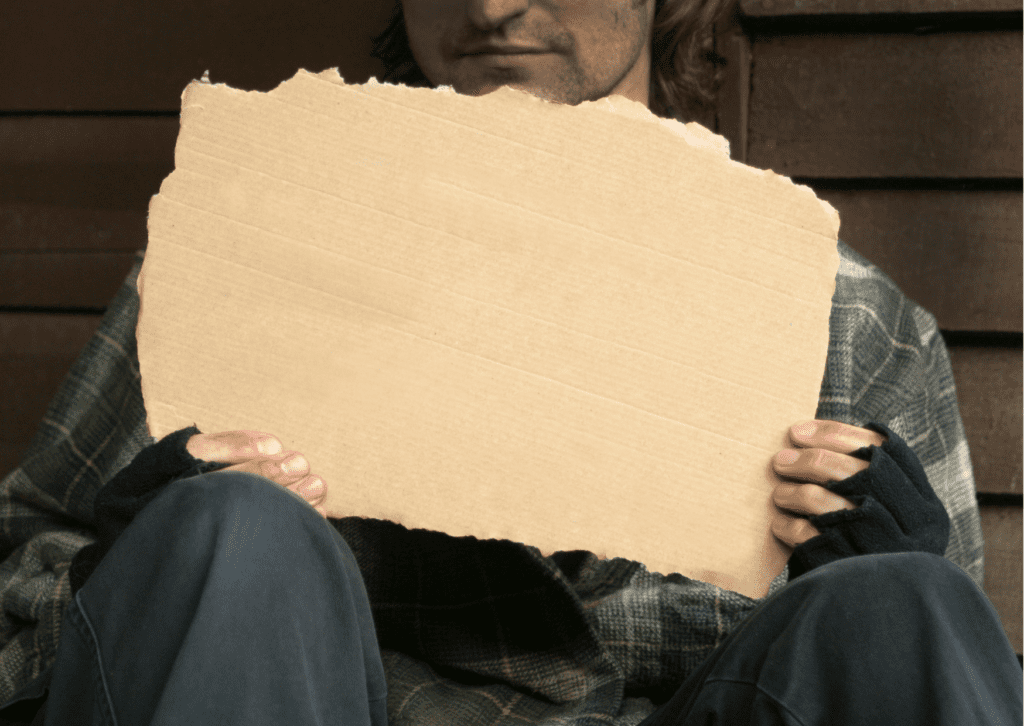 Homeless young man holding up a blank piece of brown cardboard