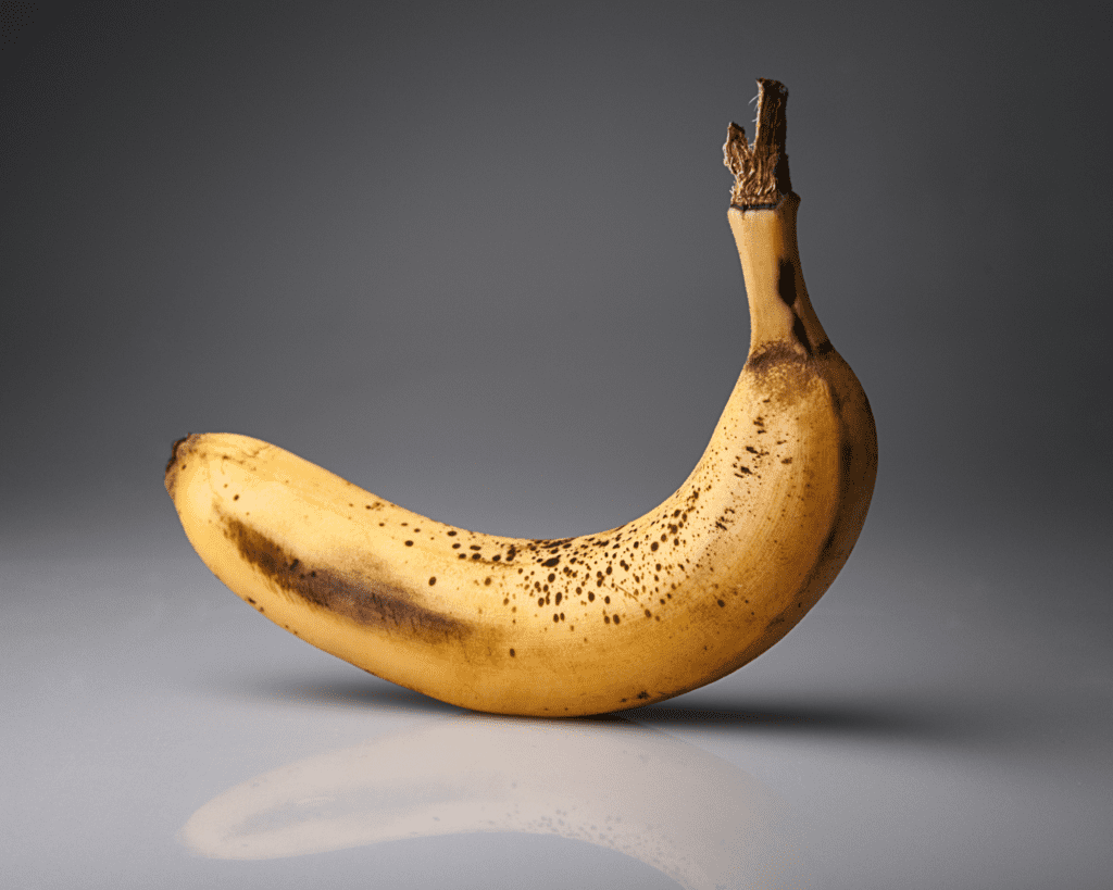 a photo of a slightly brown banana sitting upright against a grey background