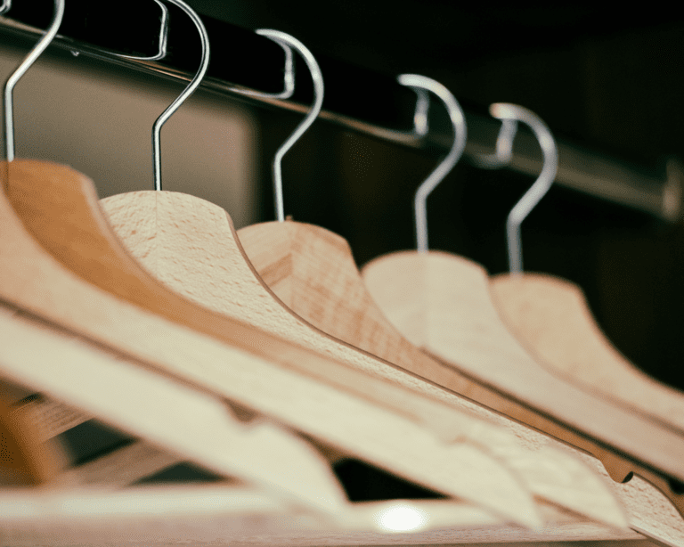 A row of wooden coat hangers hanging in a closet