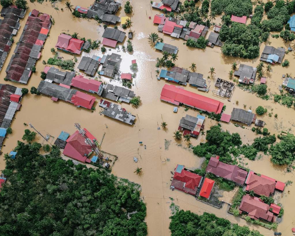 aerial view of a flooded town with only the roofs of buildings and the tops of trees visible.