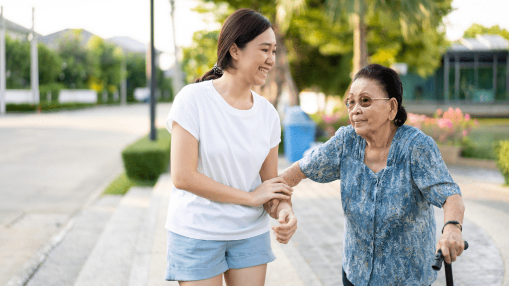 A young woman helping an older woman to walk along the street.