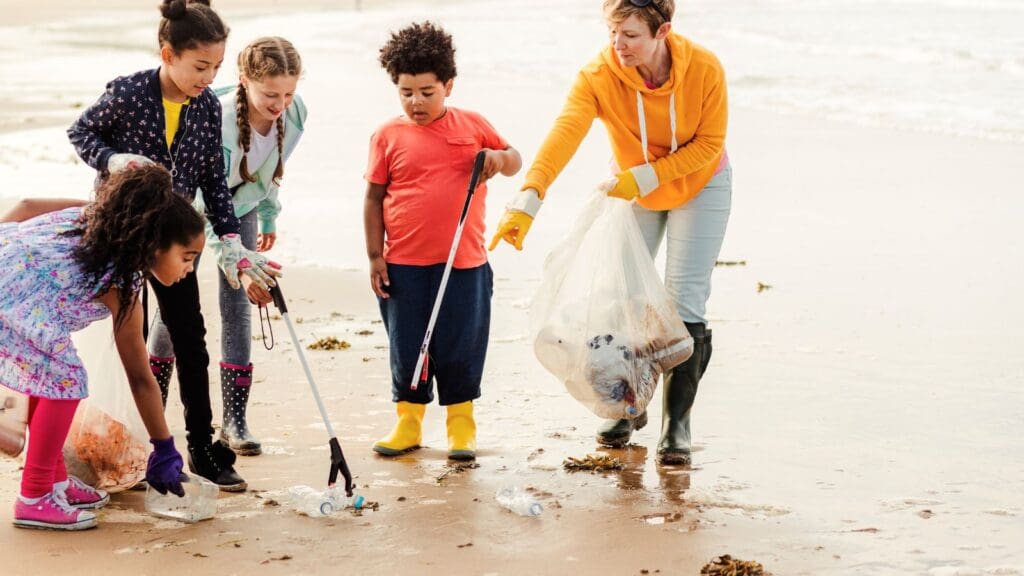 An adult woman and four children picking up plastic rubbish on a beach