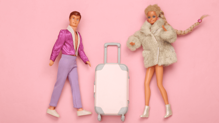 Ken and Barbie dolls with a luggage bag all set against a pink background