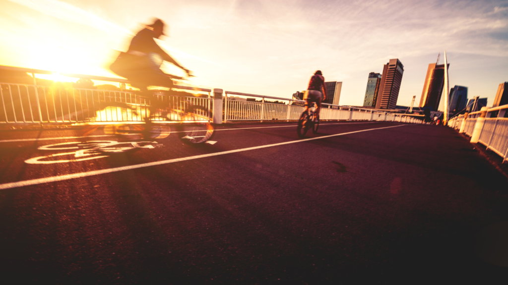 Cyclists riding over a bridge at sunset