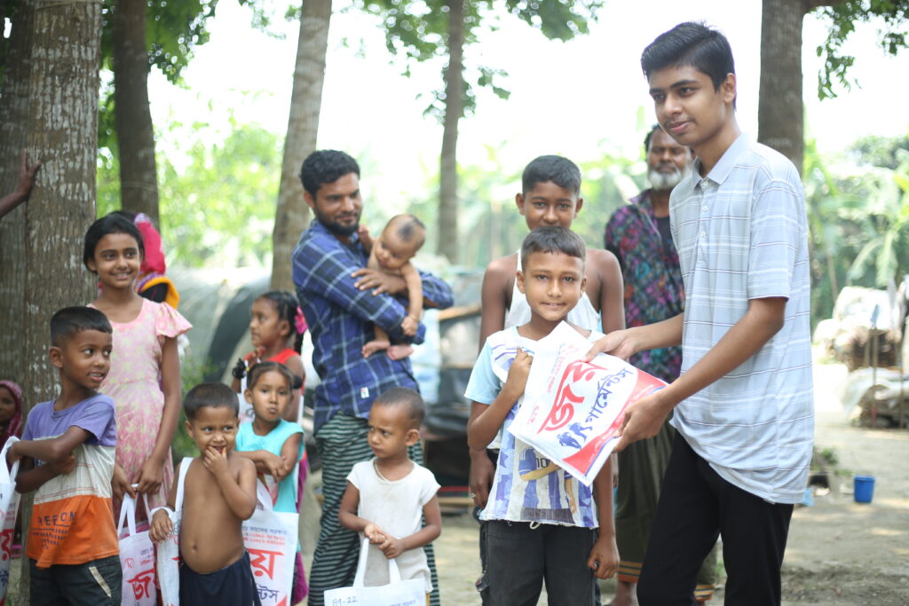 A young man (Omor Faruque) handing out supplies to families in need in Bangladesh.