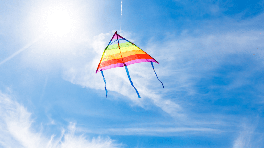 A colourful kite flying in the wind on a sunny day.