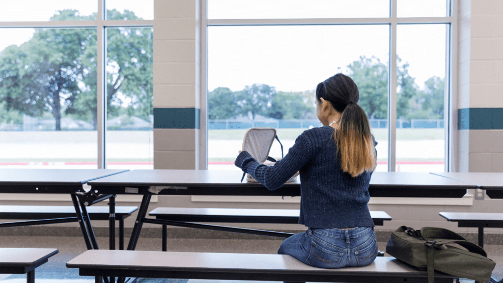 A school girl sitting on her own for lunch.