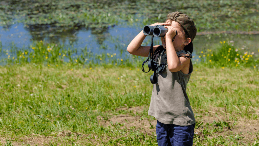 a boy birdwatching through binoculars increases well-being