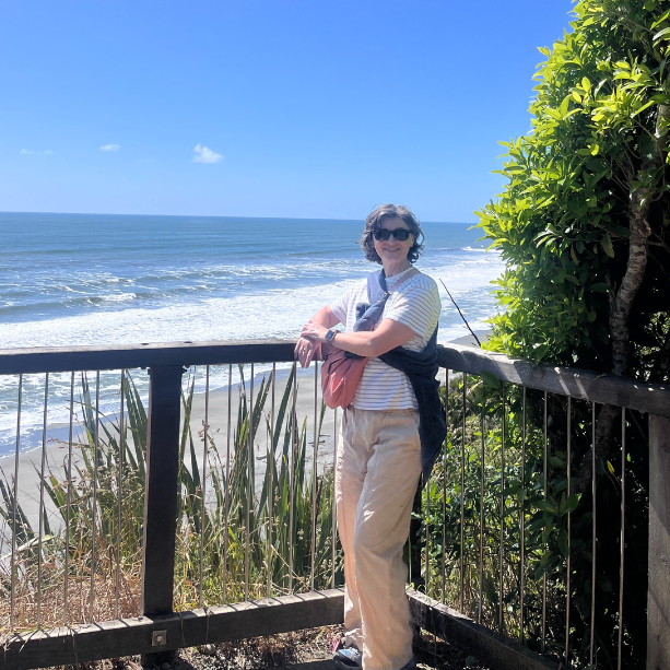 Woman standing in the foreground with the expansive western coastline of NZ in the background