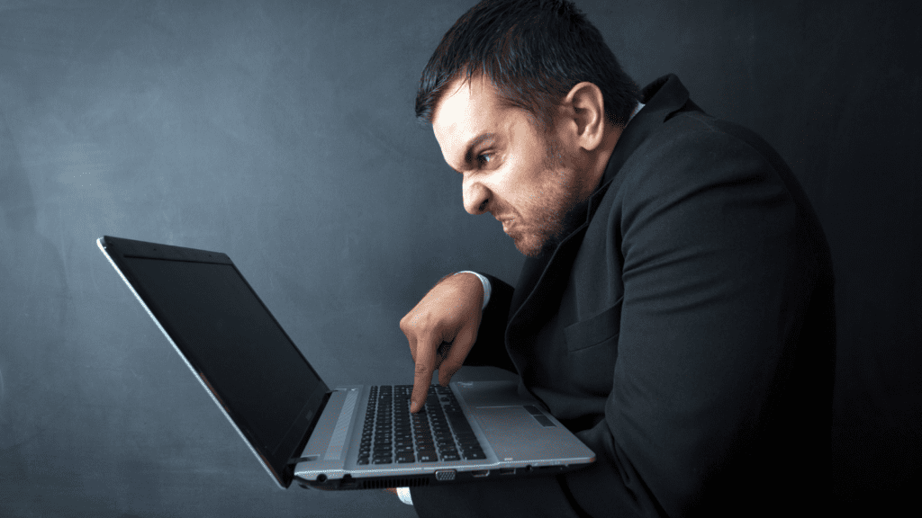 An angry man typing on a laptop.